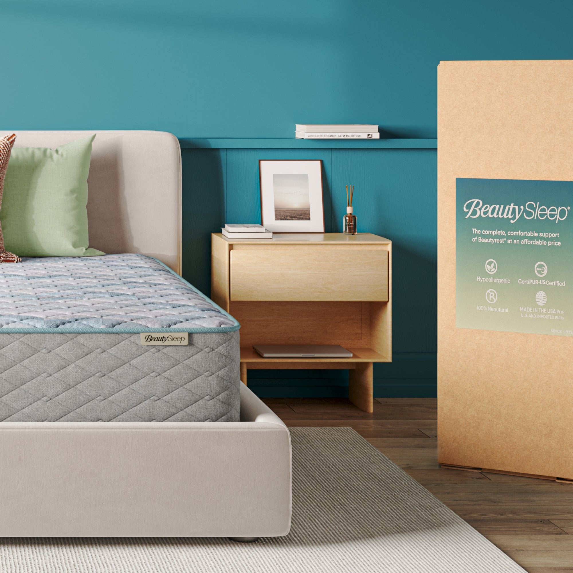 Beautysleep Mattress in a grey bedframe with 3 pillows on top of it within a bedroom setting with BeautySleep packaging to the right of it.