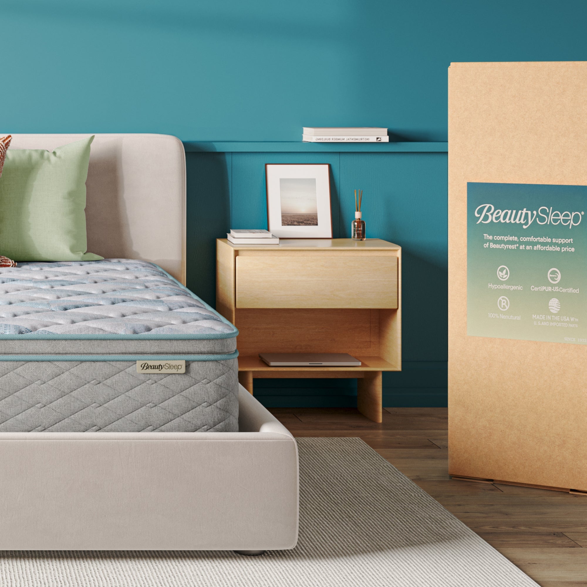Beautysleep Mattress in a grey bedframe with 3 pillows on top of it within a bedroom setting with BeautySleep packaging to the right of it.