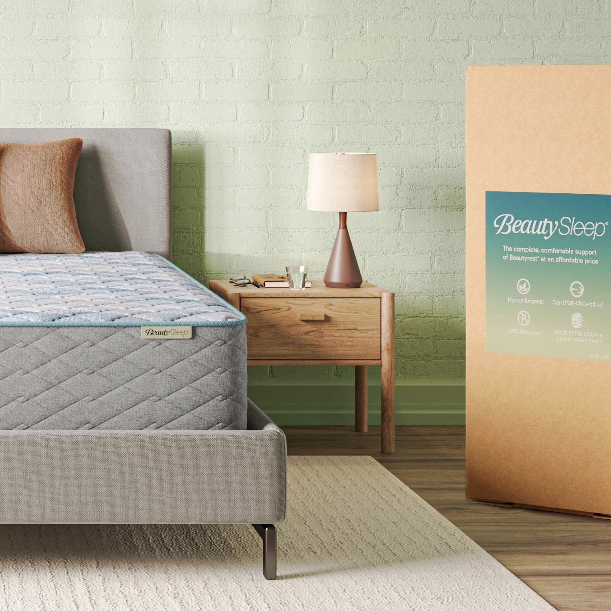 Beautysleep Mattress in a grey bedframe with 3 pillows on top of it within a bedroom setting with BeautySleep packaging to the right of it.