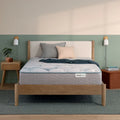 Beautysleep by Beautyrest mattress in a brown bedframe in a room setting with a lamp and nightstand.