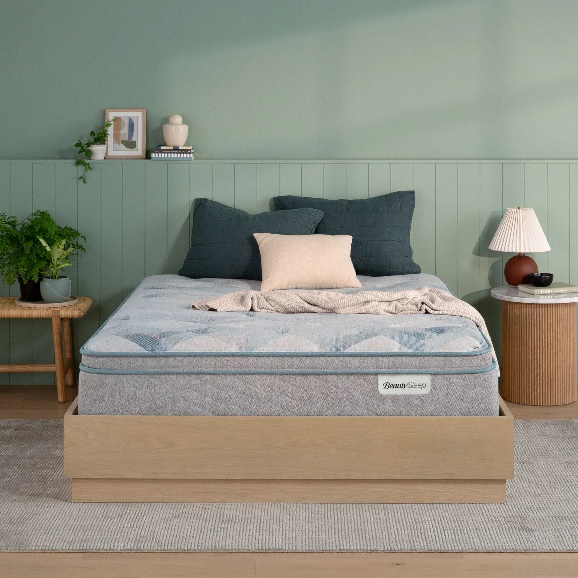 Beautysleep by Beautyrest mattress in a brown bedframe in a room setting with a lamp and nightstand.