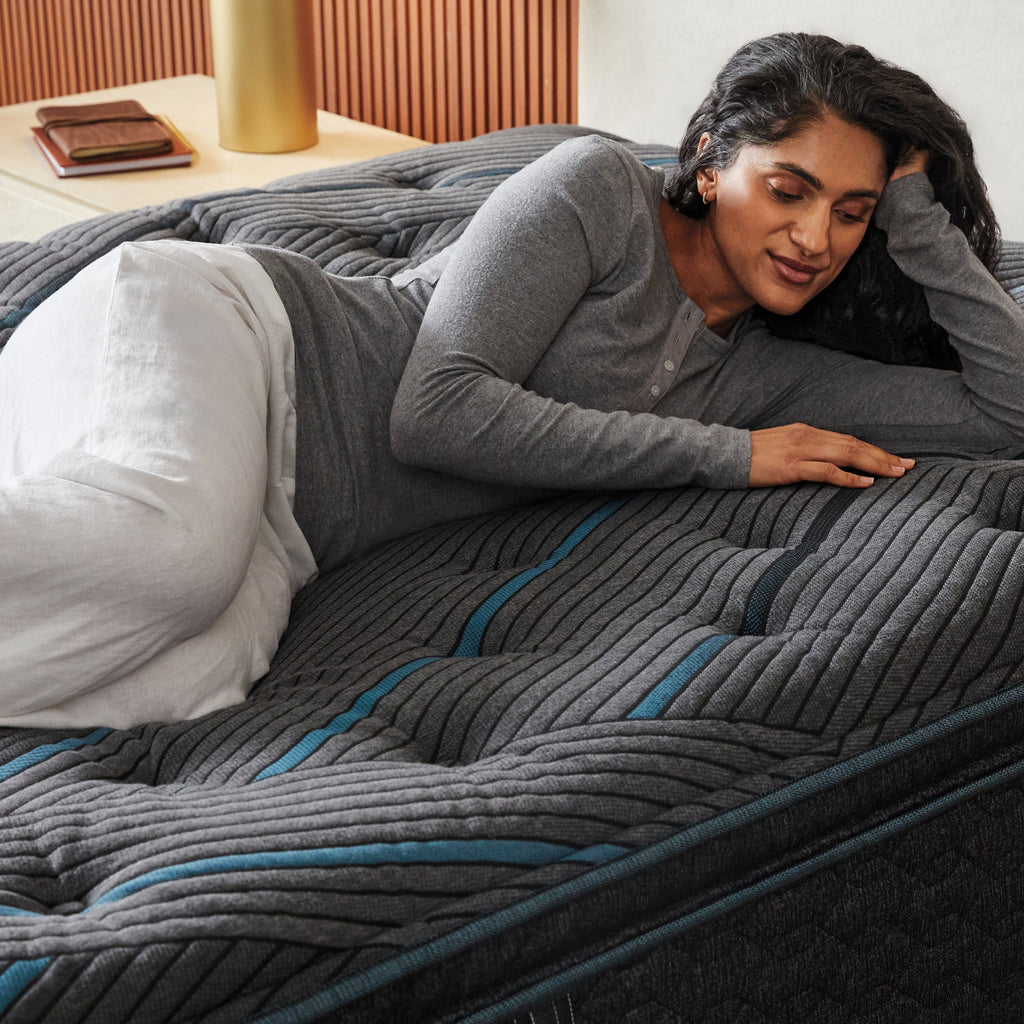 Woman laying on a Beautyrest mattress her left side rubbing the top of the mattress.
