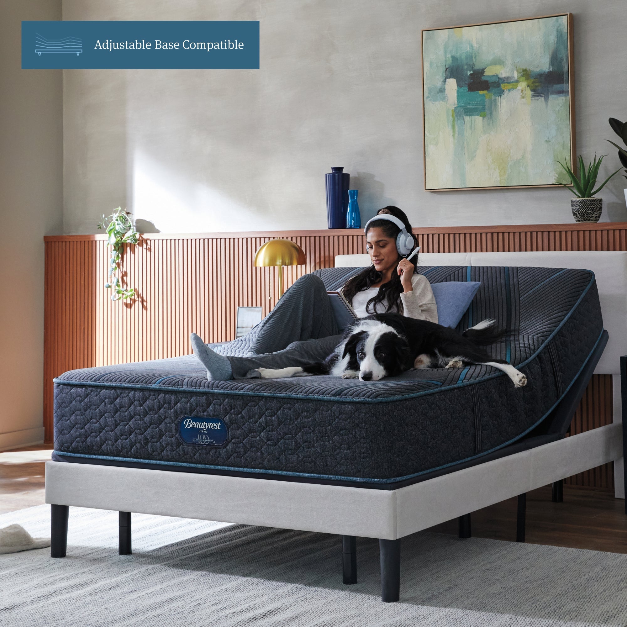 Woman sitting on Beautyrest Hybrid Plush Mattress with her dog writing on a notepad with her mattress elevated on an adjustable base.