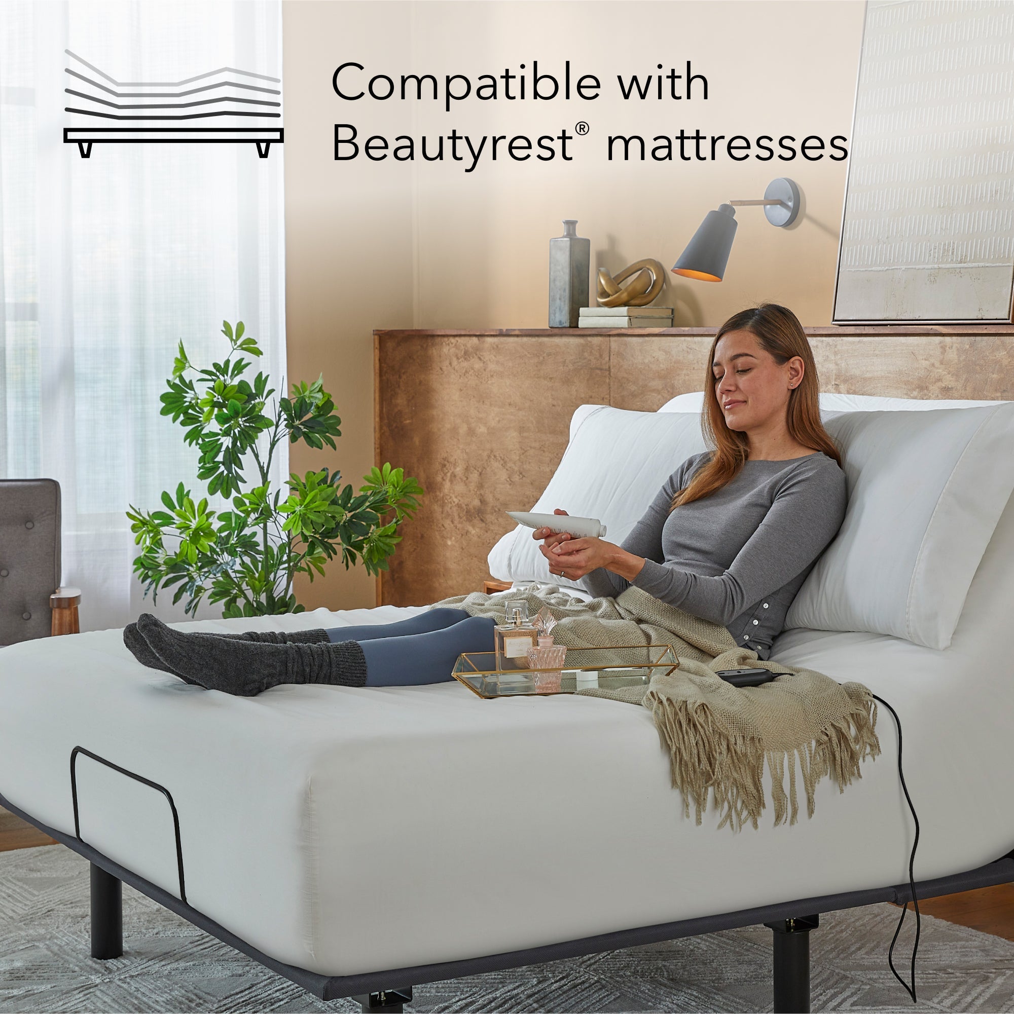 Woman sitting on a white mattress on a  Bronze baselogic adjustable base
