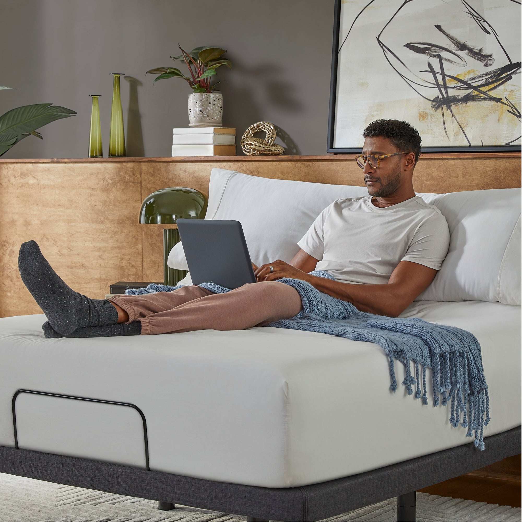 Man sitting in a Baselogic Platinum Adjustable Base with a white mattress on top of it. || level: Platinum