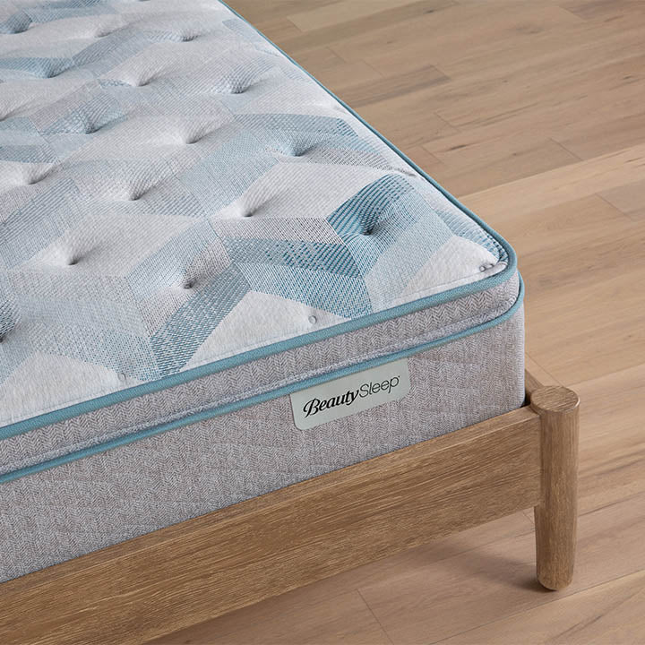 Beautysleep by Beautyrest mattress Gray quilted mattress on a wooden bed frame with 'BeautySleep' branding.