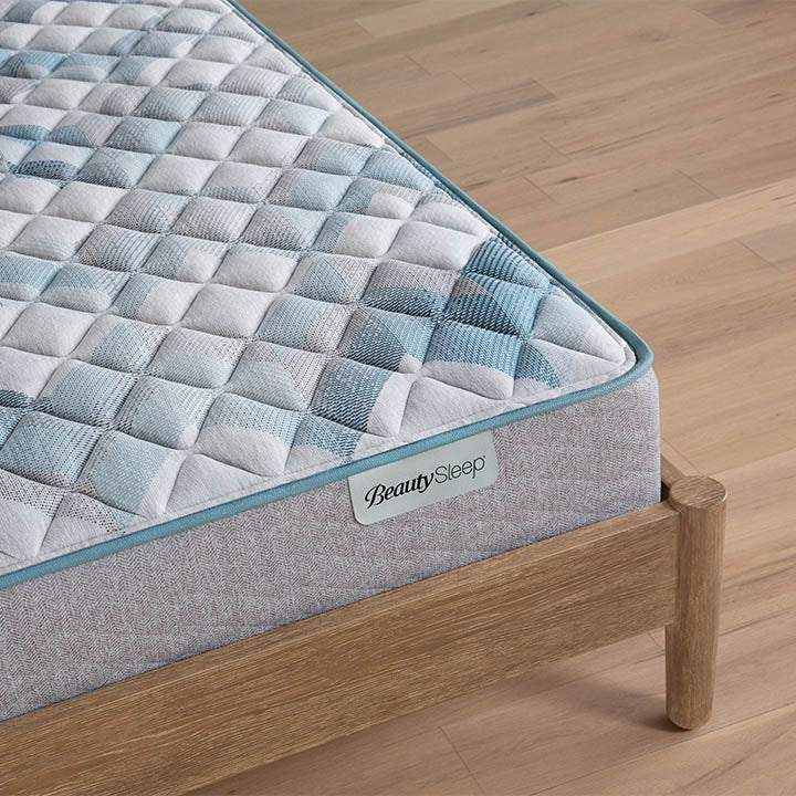 Beautysleep by Beautyrest mattress Gray quilted mattress on a wooden bed frame with 'BeautySleep' branding.